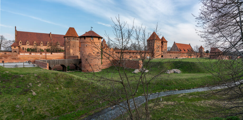 Zamek w Malborku od strony wschodniej. Widok na odbudowane elementy obronne ( baszty)na wałach von Plauena. Na wprost widoczny fragment Zamku Wysokiego, w oddali po prawej stronie dach Karwanu.