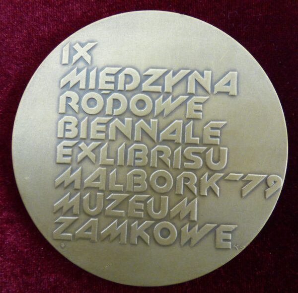 Medal owalny w kolorze srebrnym. Pośrodku napis IX Międzynarodowe Biennale EXlibrisu Malbork - 79 Muzeum Zamkowe