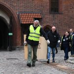 Pracownicy muzeum niosą przez dziedziniec zamkowy drewnianą skrzynię służącą do ewakuacji eksponatów.