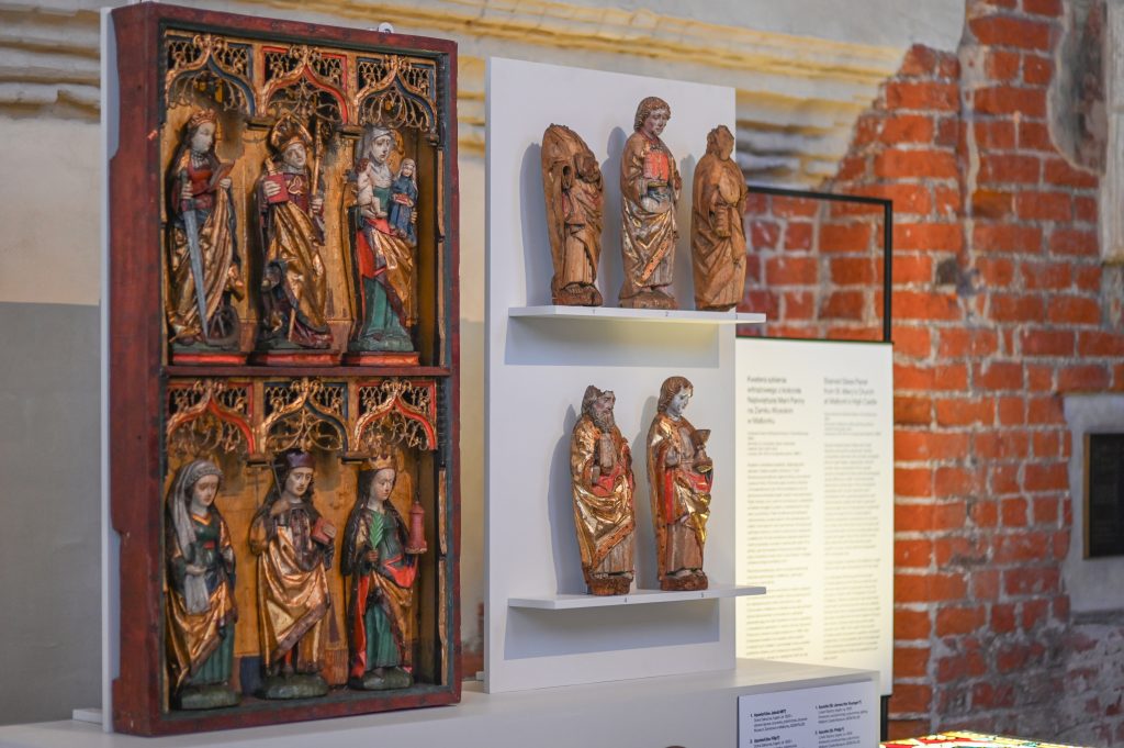 Wnętrze kościoła zamkowego. Pod ścianą na specjalnej ściance skrzydło ołtarza. W sześciu kwaterach postacie świętych. Po prawej stronie na dwóch półkach sześć drewnianych figur. Część z nich z licznymi ubytkami i uszkodzeniami.
